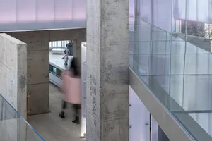 A modern industrial interior design featuring concrete walls and glass walls with a concrete column and glass window in the f