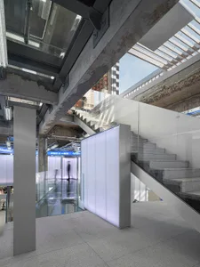 A modern industrial staircase made of concrete with glass railings and a glass partition.