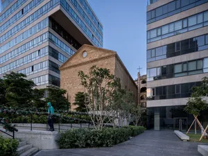 A modern office building with brick and concrete exterior and glass windows, viewed from an outdoor perspective showing the s