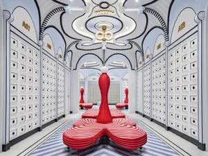 Modern retail store interior with concrete walls, white and red striped seating areas, and archways with names above them.