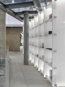 Modern shop interior showcasing white shelves against concrete pillars and a glass ceiling.