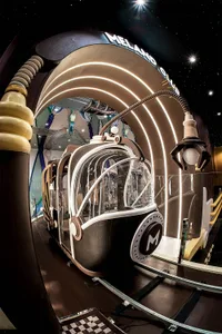 A futuristic glass structure with a curved, space-themed exterior resembling a spaceship or piece of architecture.