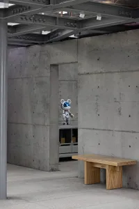 Modern industrial interior with minimalist design, featuring a concrete wall and metal beams.