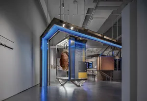 Modern industrial exhibition display featuring a large metal structure with blue lighting and various informational panels.