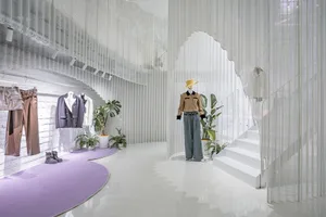 A modern fashion retail store featuring industrial design elements with metallic textures and white plastic materials.