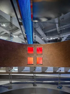 A modern exhibition interior featuring a concrete wall with illuminated panels and metallic structures.
