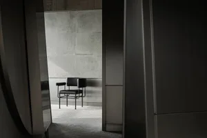 A modern interior with a concrete wall and a single black chair.