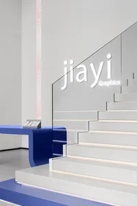 Modern office space featuring sleek white stairs with glass railings and a blue reception desk.