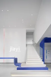 A minimalist reception area with blue accents and glass stairs.