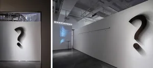 極簡設計的走廊，白色牆面上展示著大型問號。
