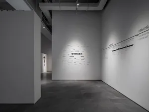 An exhibit hall with minimalist design, featuring gray tiles, white walls, and a modern aesthetic.