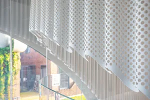 A close-up view of modern interior design featuring a metal perforated screen with a geometric pattern.