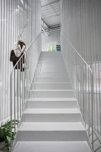 Modern interior design featuring metallic stairs with white walls and railings