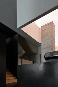 Modern interior design featuring wooden stairs and a concrete chimney.