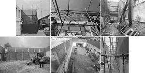 Black and white image showing a building under construction with scaffolding and various materials scattered around the site.