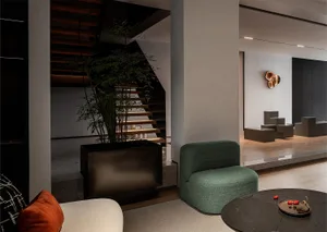 Modern living room with a taupe sofa, green armchair, and concrete floor.