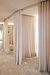 A modern minimalist interior featuring space-partitioning curtains made of fabric.