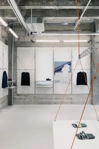 A retail display area with concrete walls, white shelving, and clothing items hanging.
