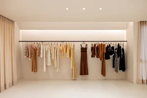 A clothing rack featuring neutral-colored garments against a white background.