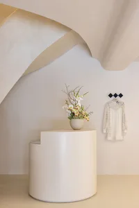 A minimalist modern space with white cylindrical objects and floral arrangement.