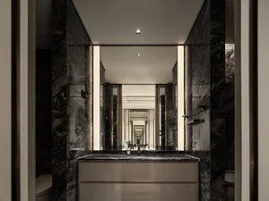 Modern bathroom with marble walls and floor, featuring a sleek vanity and mirror.