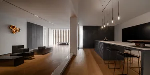 A modern residential kitchen with concrete counter tops, wood flooring, and metal furniture.