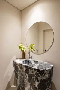 Modern bathroom with a sleek, curved marble vanity and a round mirror above it.