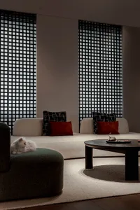 A modern living room with a white sofa, patterned cushions, and a round wooden coffee table.
