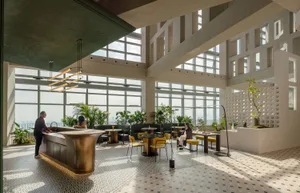 Modern design cafe bar with metal counter, concrete seating area, and lush green plants