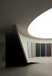 A modern interior space displaying various neutral color samples on a curved white wall with a large skylight above.