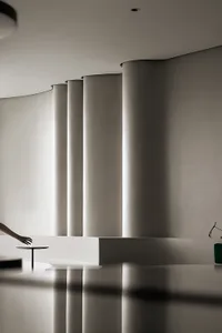 Modern minimalist interior space with concrete columns and smooth, reflective floor.