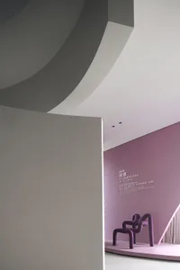 A modern, purple-themed room featuring unique, sculptural furniture covered in velvet upholstery.