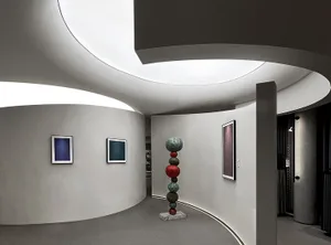 Interior view of a modern art museum with concrete walls, curved ceiling, and contemporary art displays.