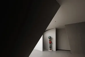 A modern interior space featuring a sculpture made of stacked, multicolored spheres on a pedestal.
