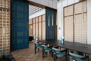Modern restaurant interior with wooden tables, metal chairs, and glass partitions.