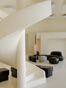 Modern living area with white plaster walls, white furniture, and black accents