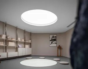 A serene minimalist living room with a concrete floor and wooden elements, featuring a large circular window.