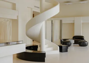Modern store interior with white stone walls, black metal accents, and black leather seating.