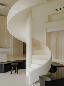 A modern retail space with a minimalist design, featuring a white spiral staircase and a white dress hanging on the wall.