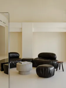 A modern living space with a black leather armchair, round concrete coffee table, and minimalist decor.