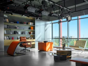 A modern office interior featuring metallic accents, a leather desk, and glass elements.