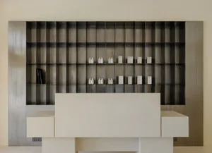 A minimalist modern interior with a metal shelving unit displayed against a beige wall.