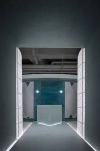 A minimalist interior featuring concrete walls and a white cube structure.