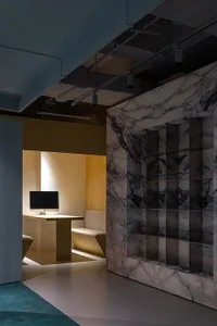 Modern office interior featuring white marble accents, sleek furniture, and overhead lighting on a gray floor with teal accen