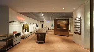 Retail clothing store interior featuring a tiled floor and wooden display tables.