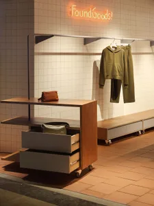A modern clothing store interior featuring a wooden display stand and shelving.