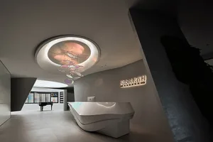 A modern reception desk made of glass with an industrial lighting fixture overhead.