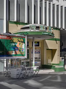 A retro shopfront with a concrete exterior and green signage.