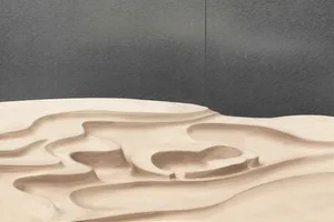 Abstract sculpture of ripples and curves formed in beige sand against a black background, resembling natural formations.