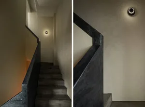 Industrial-style staircase with sleek, black concrete steps and a modern wall-mounted light fixture.